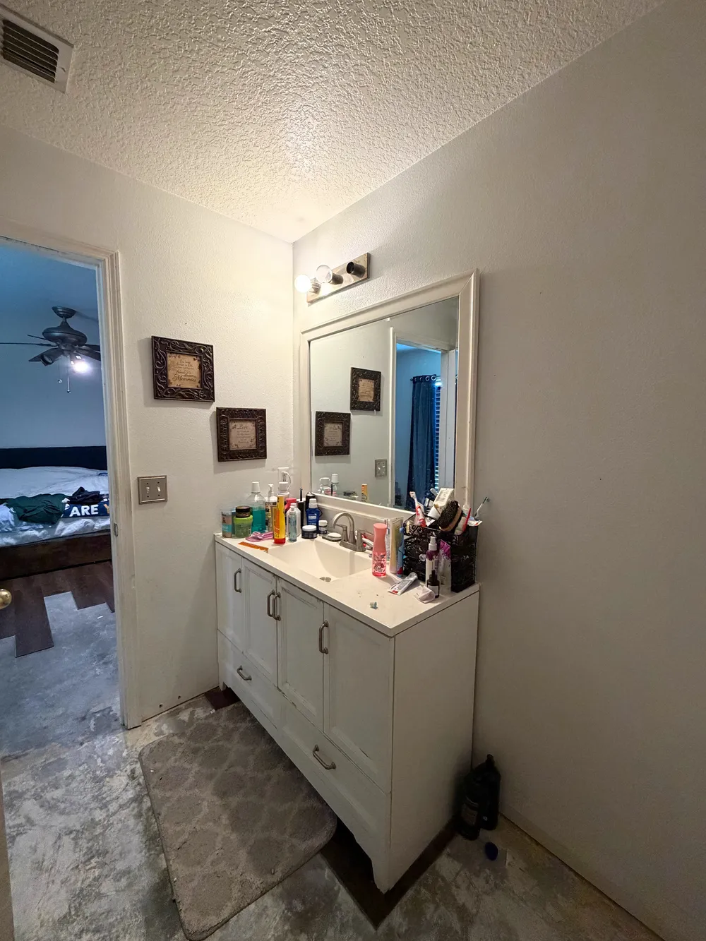 Original single vanity and mirror with the bathroom flooring already removed.