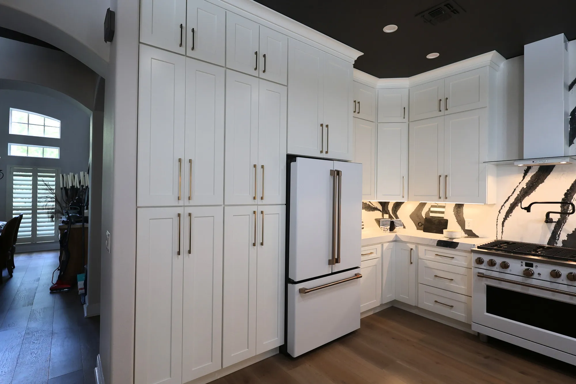 Ceiling-height white pantry cabinets and refrigerator beside the Blackwater cooking wall.