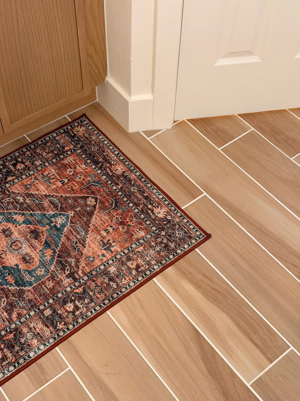 Wood-look floor and rug detail in the Calle bathroom.