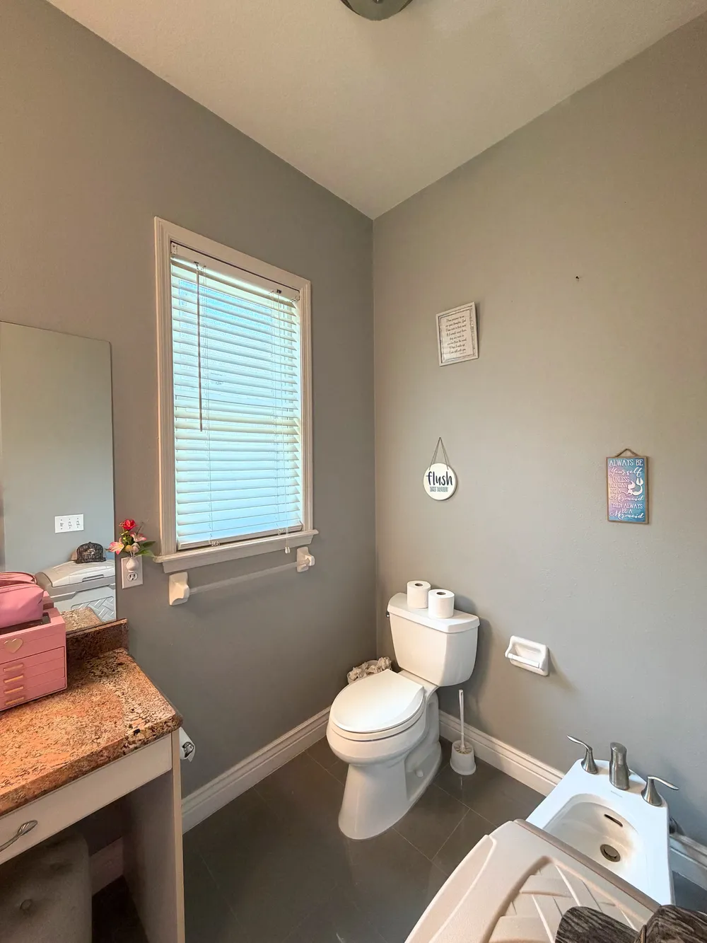 Original Estancia bathroom toilet and bidet beside a vanity with a stone counter.