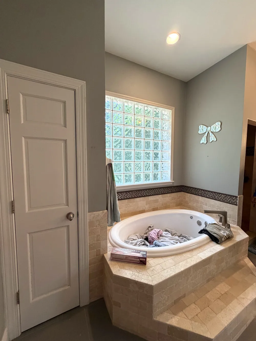 Original built-in bathtub below a glass-block window beside the enclosed shower.