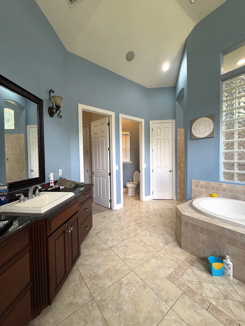 Original Grand Revival bathroom with blue walls, dark wood vanity, beige tile and a built-in jetted tub.