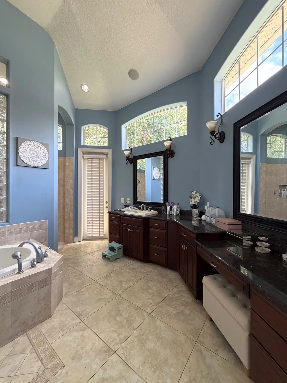Original long dark wood vanity and makeup counter below high windows in The Grand Revival bathroom.
