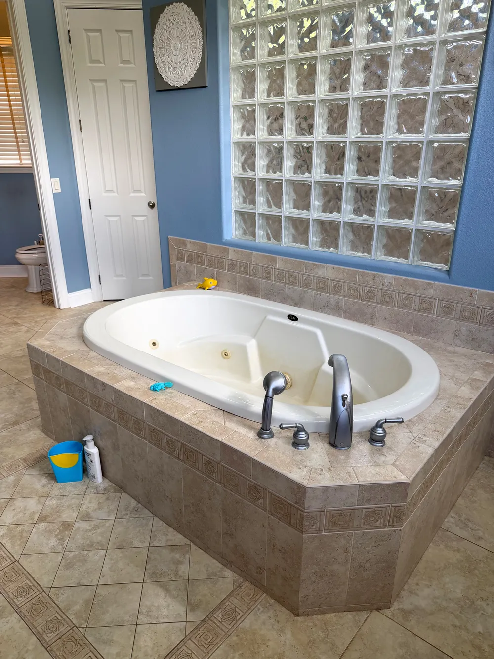 Close view of the original built-in jetted bathtub, tiled deck and glass-block wall in The Grand Revival bathroom.