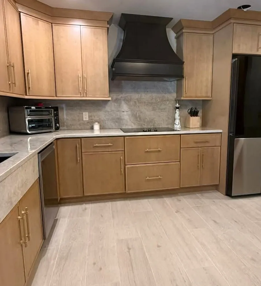Lake Roper cooking wall with a dark hood, cooktop, quartz backsplash and wood-tone cabinets; a ceiling opening remains visible at upper right.