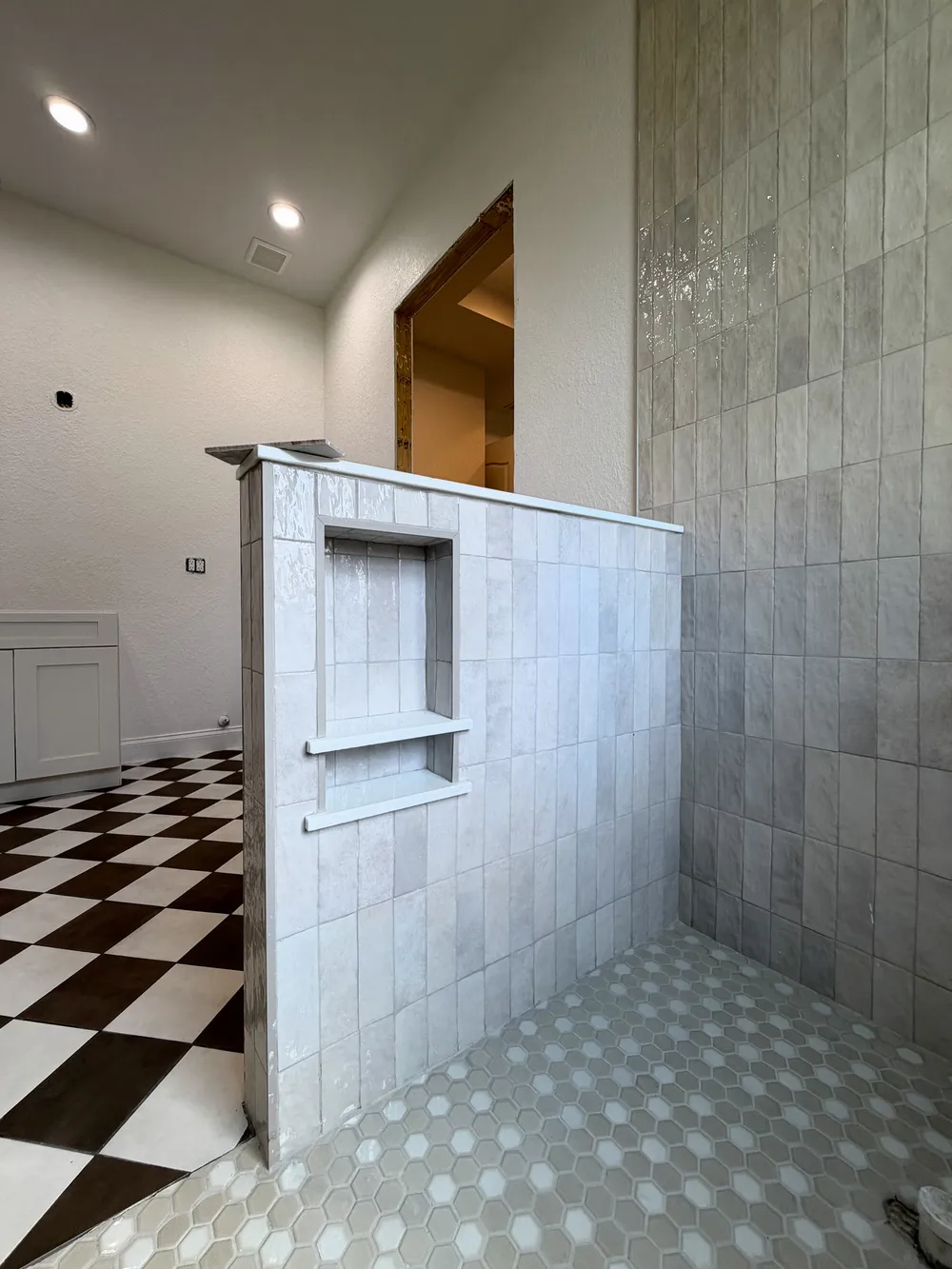 Shower half wall and niche relationship in the Pompano bathroom.