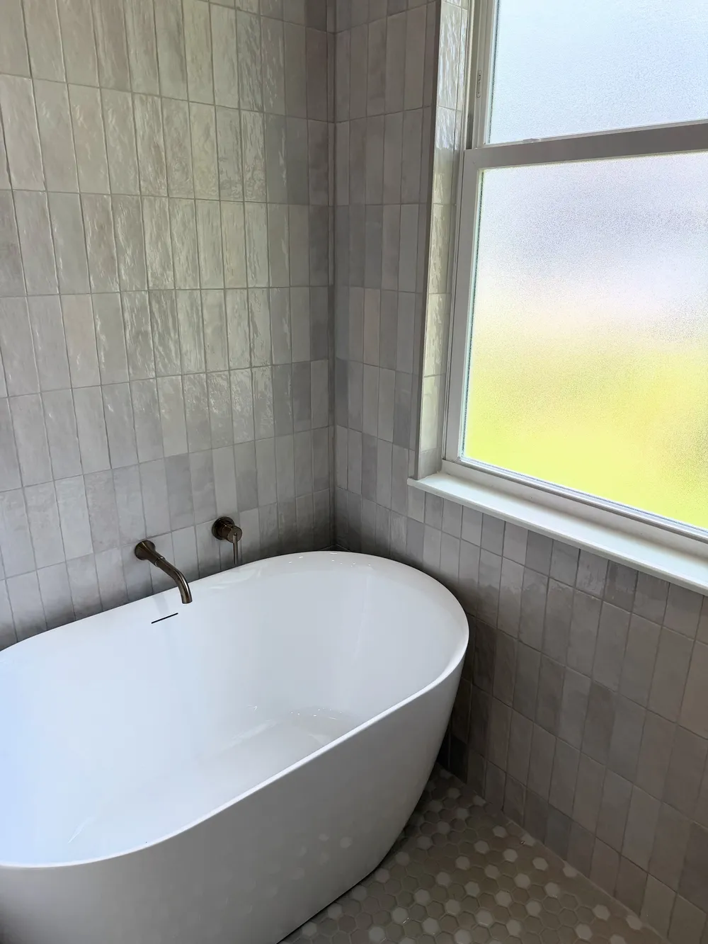 Freestanding tub by frosted window in the Pompano bathroom.