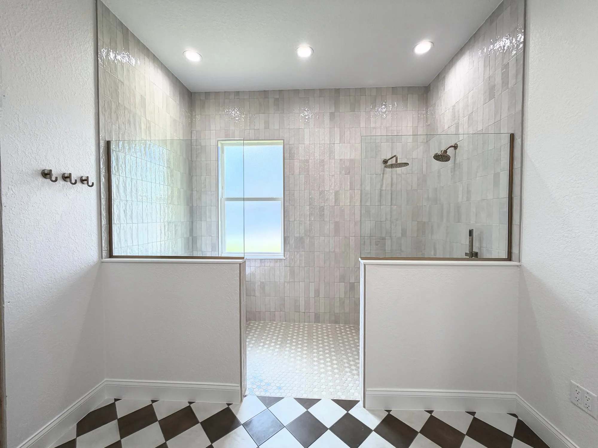 Finished Pompano bathroom with textured shower tile, glass partitions, bronze-tone fixtures and a checkerboard floor.