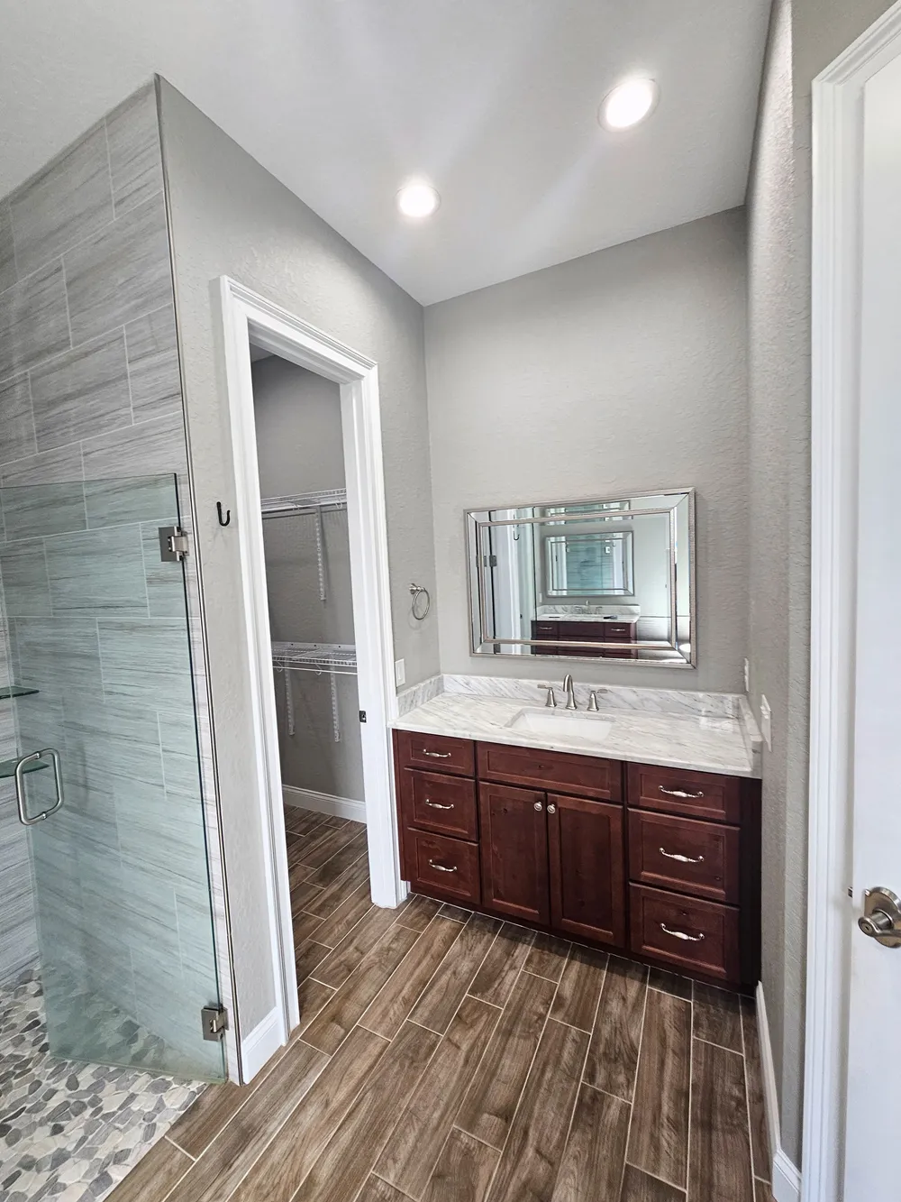 Dark wood vanity, framed mirror, closet doorway, and shower entrance before the Pompano remodel.