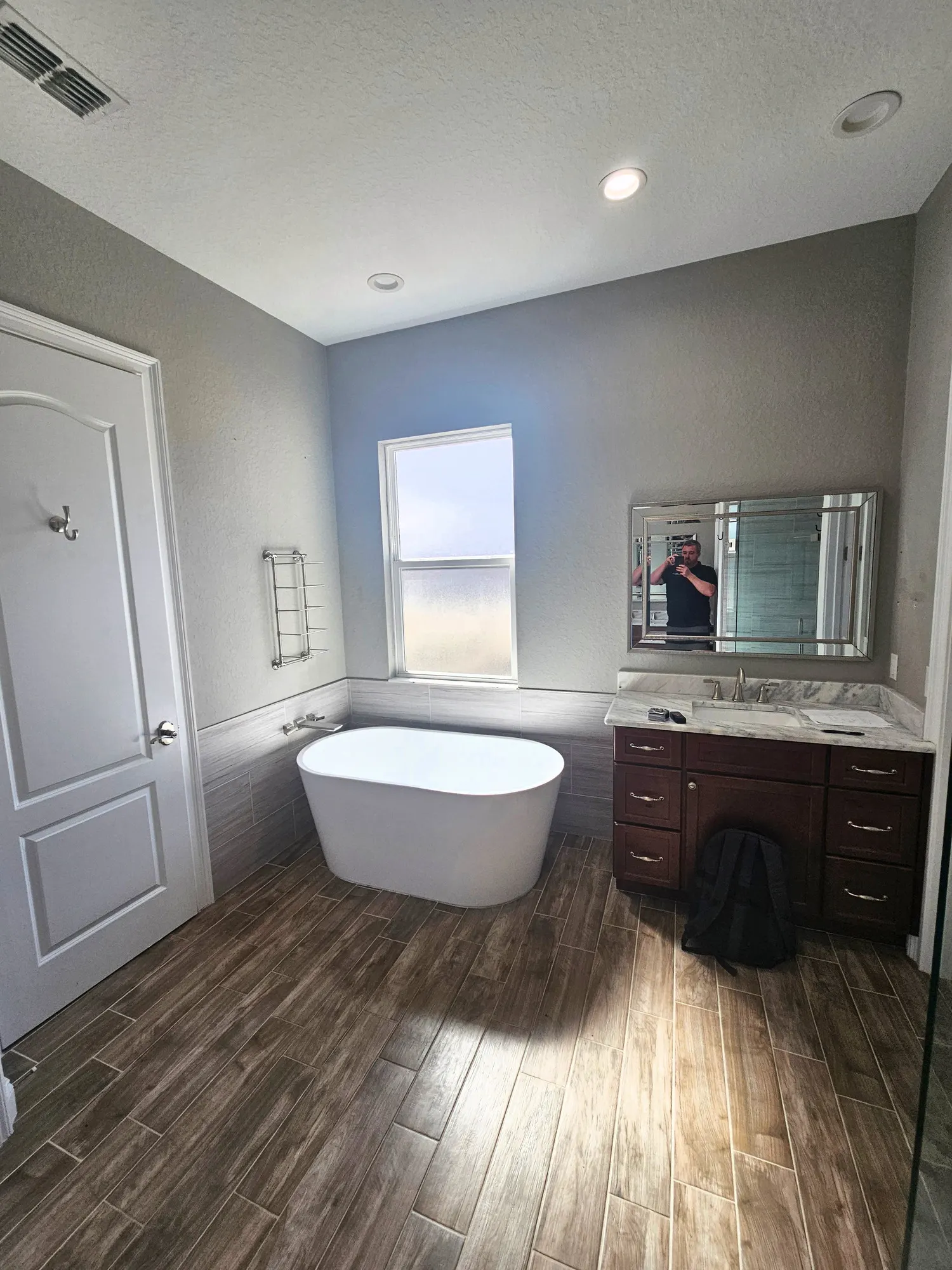 Pompano bathroom before remodeling, with a freestanding tub beneath the window and a dark wood vanity.