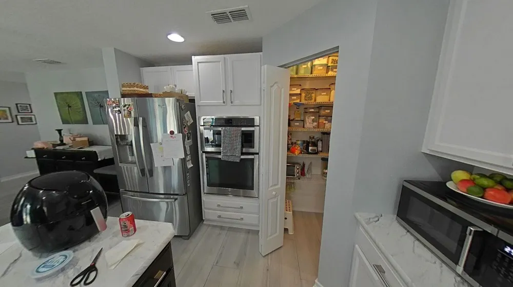 Earlier refrigerator and wall-oven cabinetry beside an open pantry and the original narrow island, photographed during work.